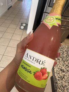 someone holding up a bottle of strawberry wine