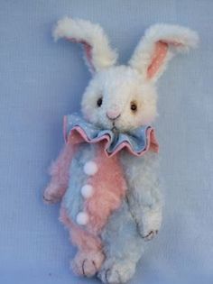 a white stuffed rabbit with a pink and blue bow tie on it's neck