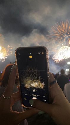 someone holding up their cell phone to take a photo of fireworks