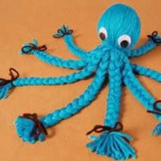 an octopus made out of blue yarn with eyes and hands on it's back