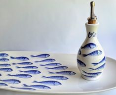 a blue and white bottle with fish on it sitting on a plate next to a lighter