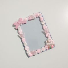 a pink and white photo frame sitting on top of a table next to a teddy bear