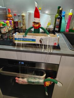 an elf is sitting on top of the oven with toothbrushes in front of him