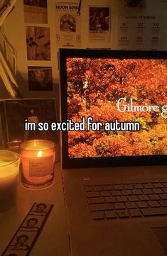 an open laptop computer sitting on top of a desk next to a candle and pictures