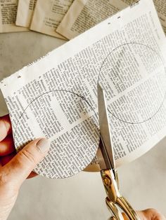 a person cutting through some newspaper with scissors and paper clippings next to them