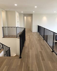 an empty room with wooden floors and black railings