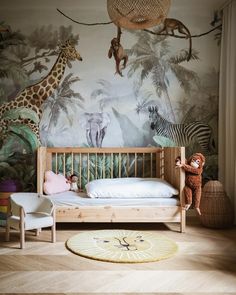 a child's bedroom with jungle wallpaper and wooden furniture