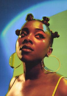 a woman with large hoop earrings on her head, wearing yellow dress and gold ear rings