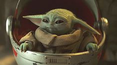 the child yoda from star wars is sitting in a metal bucket with headphones on