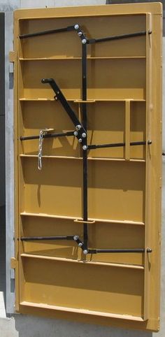 a large yellow box with metal bars and chains attached to the sides, hanging from it's side wall