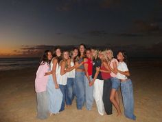 a group of women standing next to each other on top of a sandy beach at night