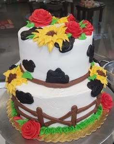 a cake decorated with sunflowers, roses and a fence on a silver platter