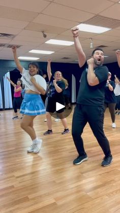 a group of people dancing in a dance studio with one man holding his hands up