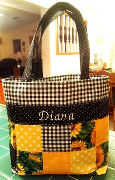 a black and white checkered bag with sunflowers on the front is sitting on a table