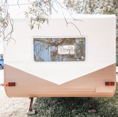 an rv is parked in the grass with its windows open and trees reflected in the window