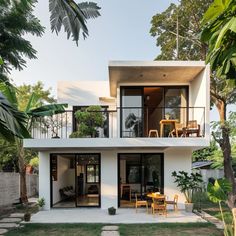 the house is surrounded by lush vegetation and has two levels that lead to an upper level balcony