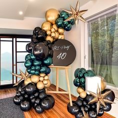 the balloon arch is decorated with black, gold and green balloons that spell out 40