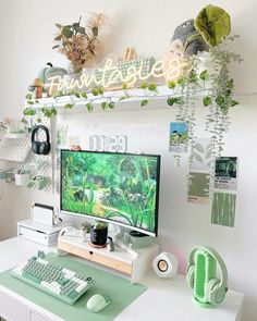 a desk with a computer, keyboard and mouse on it in front of a plant filled wall