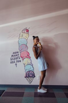 a woman standing in front of a wall with an ice cream cone painted on it