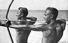 two men are on the beach with their backs to each other and one is holding a bow