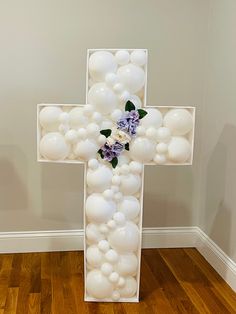 a cross made out of balloons and flowers on the floor in front of a wall