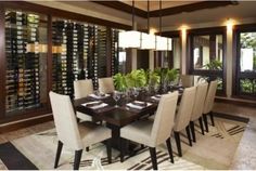 a dining room table and chairs with wine bottles on the wall