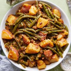 a white bowl filled with green beans and potatoes on top of a blue table cloth