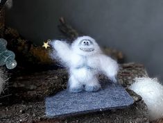 a white stuffed animal standing on top of a piece of felt