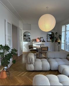 a living room filled with lots of furniture and a white lamp hanging from the ceiling