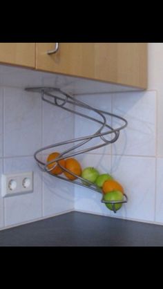 a kitchen counter with some fruit on top of it and a metal shelf above the sink