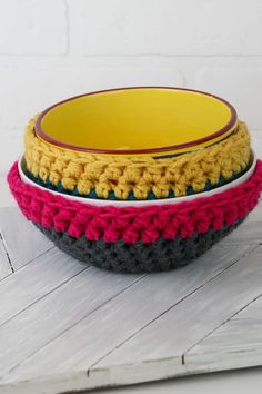 three crocheted bowls sitting on top of each other in different colors and sizes