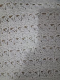 a white crocheted blanket sitting on top of a bed