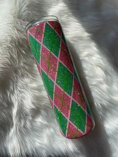 a pink and green glittered cup sitting on top of a white fur covered floor