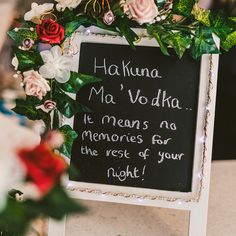 a chalkboard sign with writing on it and flowers around the edges that reads hakuna ma'vo dha, it means no memories for the rest of your night