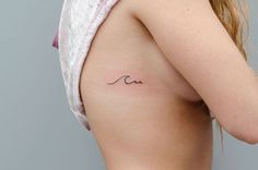 the back of a woman's shoulder with a small wave tattoo on her left side