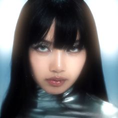 a woman with long black hair and blue eyes wearing a shiny silver outfit is looking at the camera