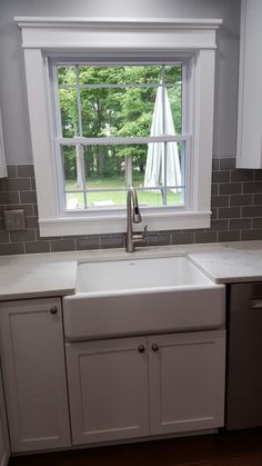 a white kitchen sink sitting under a window