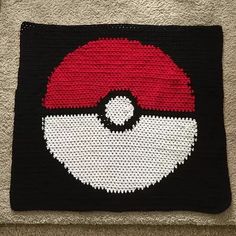 a crocheted square with a red and white pokeball on it's side