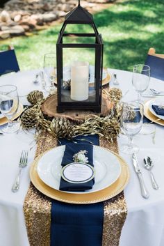 the table is set with plates, silverware and a lantern on top of it