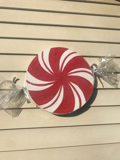 a red and white peppermink candy cane sitting on the side of a building