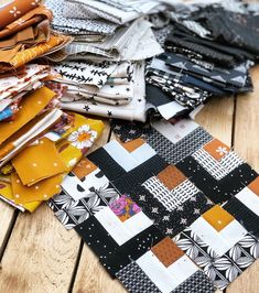 a pile of different colored fabrics sitting on top of a wooden floor next to each other