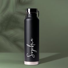 a black and white water bottle with the word love on it sitting on a green surface