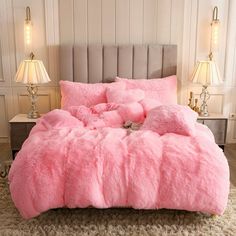 a bed covered in pink fluffy blankets and pillows