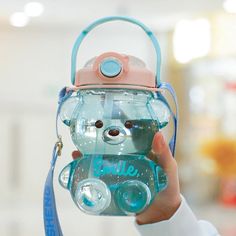 a person holding a water bottle with a bear on it's side and a blue strap around the neck