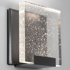 a square light fixture mounted on the side of a wall with white stars coming out of it