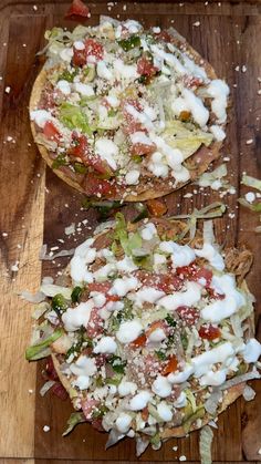 two pizzas sitting on top of a wooden cutting board covered in cheese and toppings