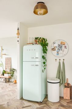 a white refrigerator freezer sitting in a kitchen next to a potted green plant