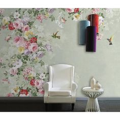 a white chair sitting in front of a wall with flowers on it