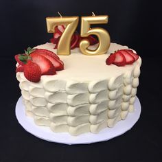 a white cake topped with strawberries and the number 75