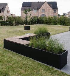 a large black planter sitting on top of a lush green field next to a building